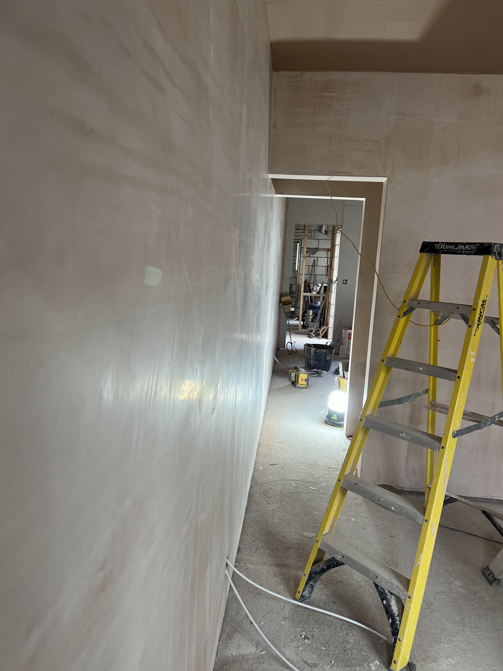 A long freshly plastered wall with a stepladder in the doorway