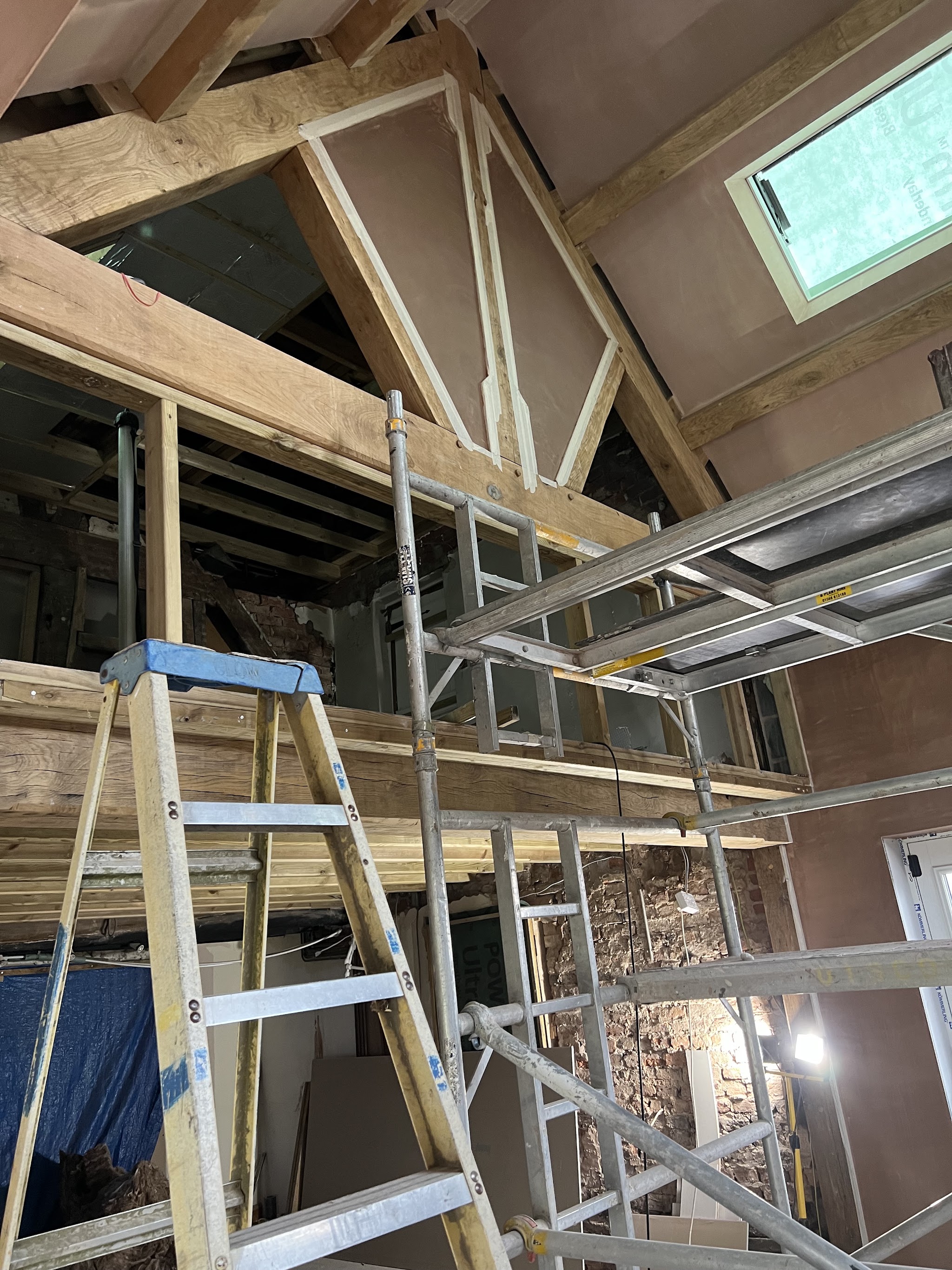 Scaffold and ladders inside a tall vaulted room being plastered