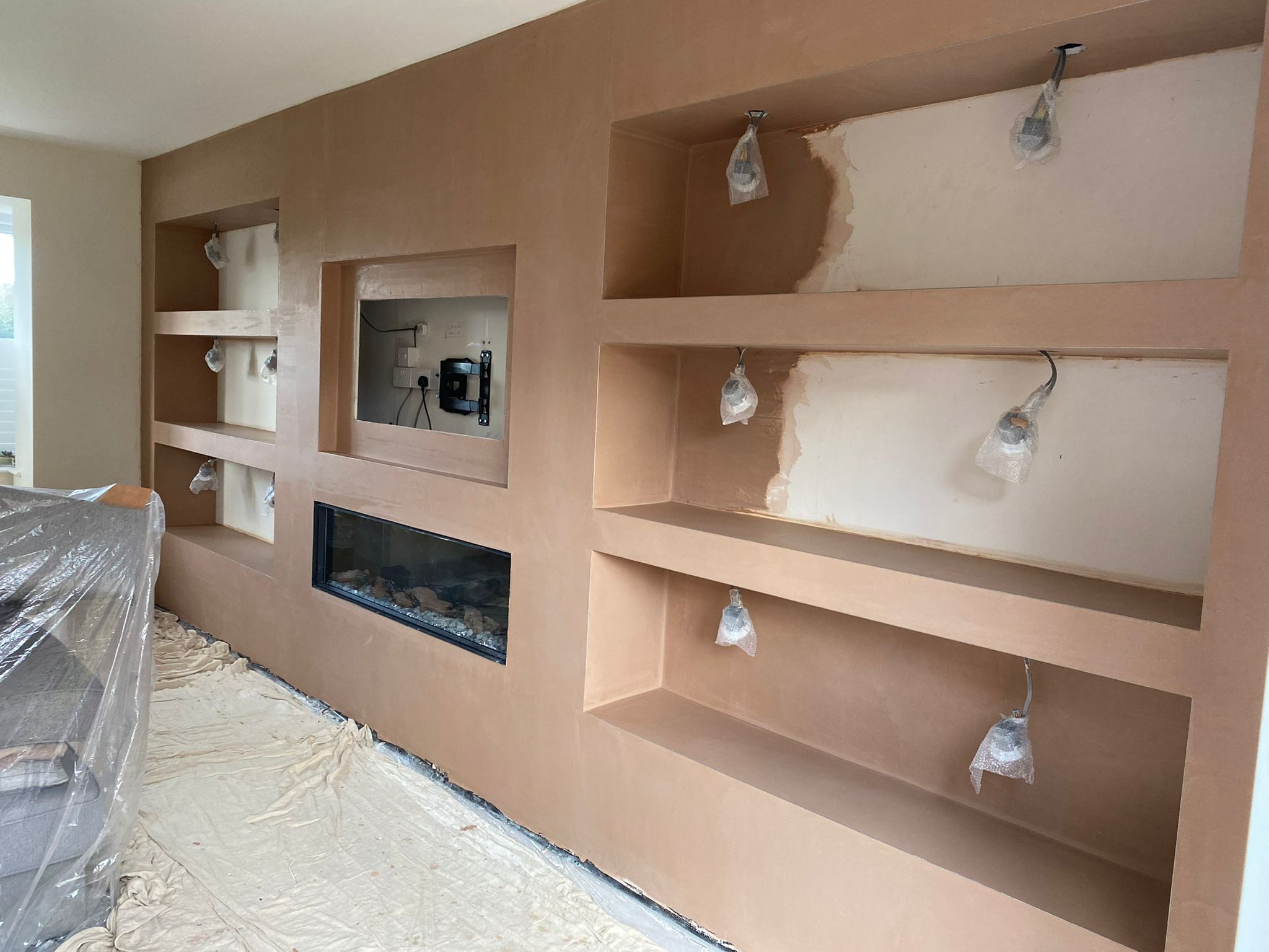 A media wall with alcove shelves part way through plastering