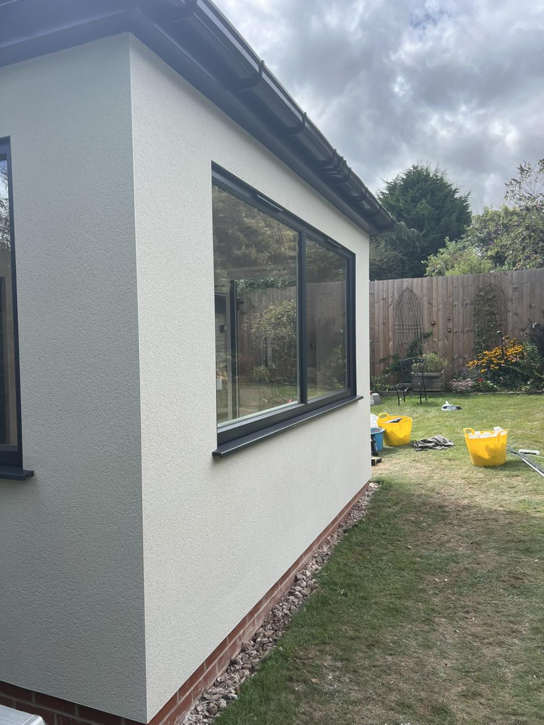 The side of a single-storey extension finished in cream render