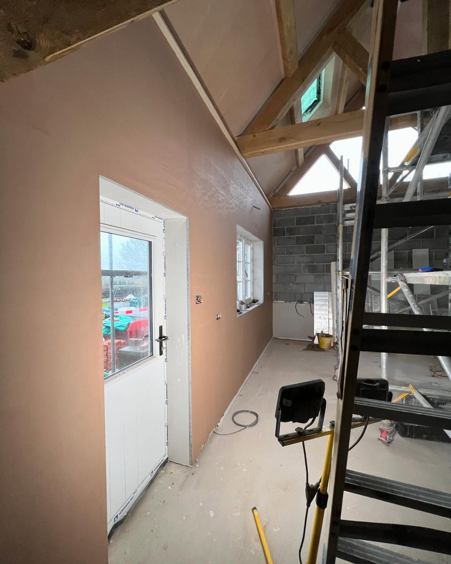 A vaulted room with exposed roof timbers, freshly plastered