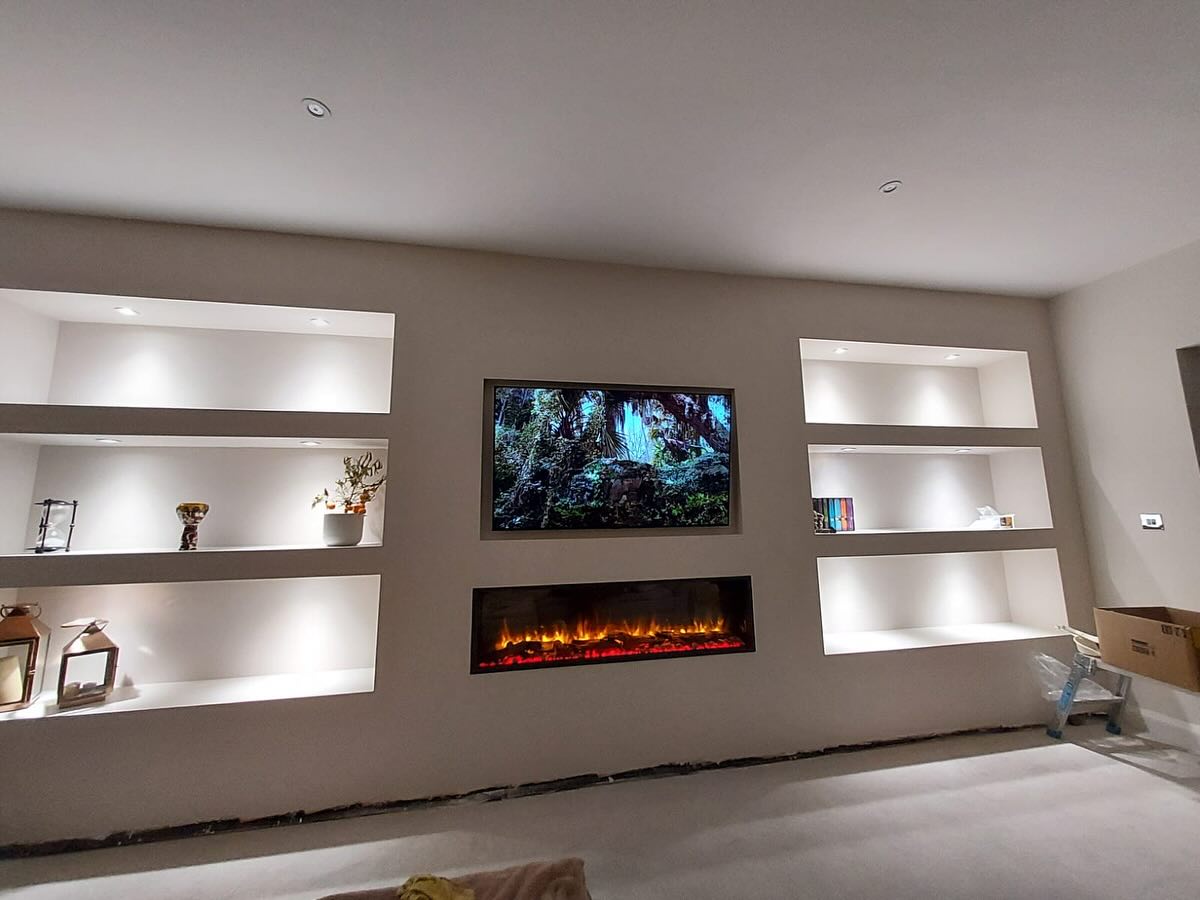 A finished media wall with lit alcoves, a television and an electric fire